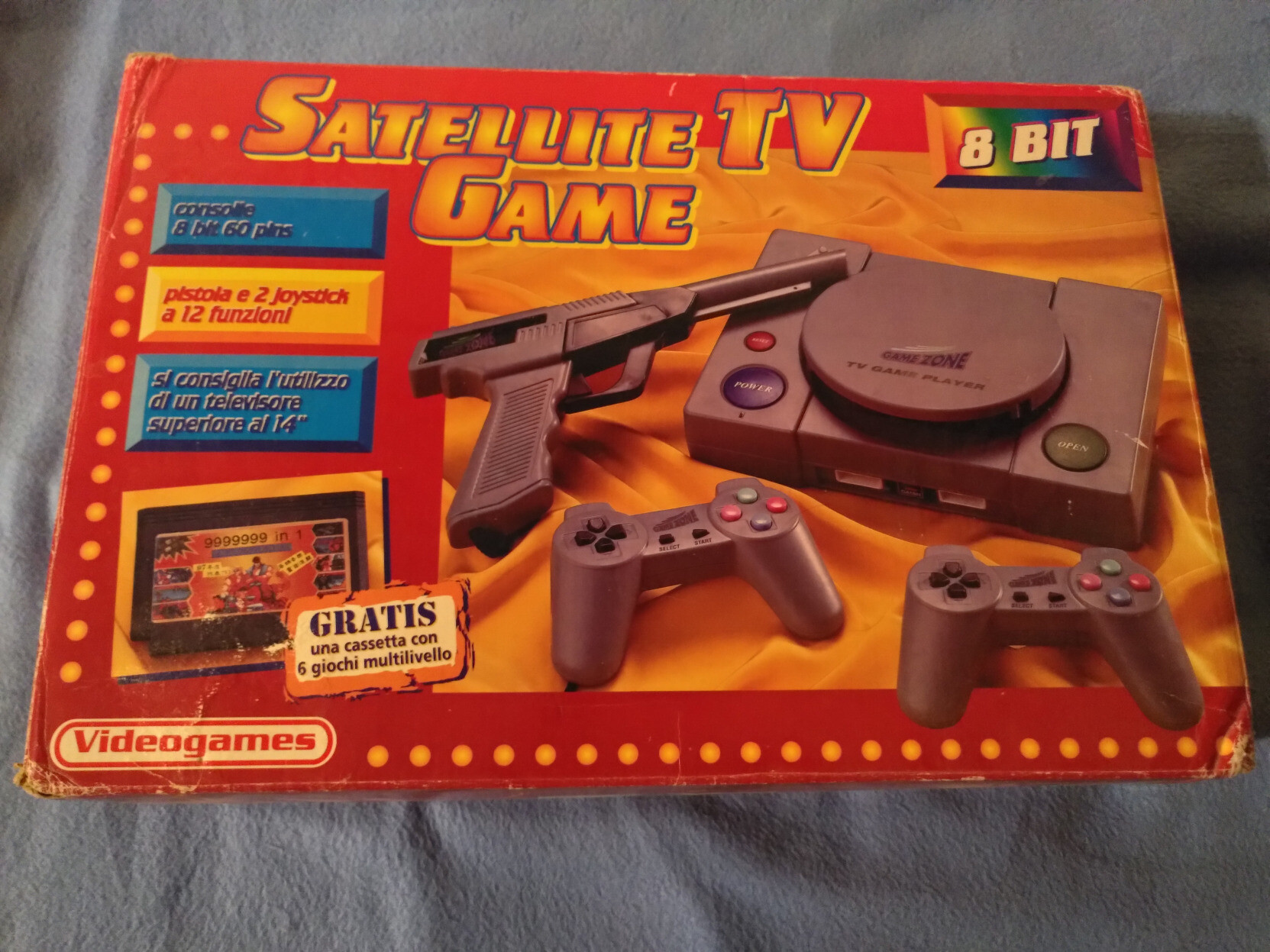 La boite dans laquelle était rangée la console, à dominantes rouge et jaune vif, avec une photo des éléments inclus, et le logo de Nintendo imprimé dessus dont le texte a été remplacé par "Videogames". La console est nommée "Satellite TV Game 8-Bit" d'après la boite, mais le logo "GameZone" est imprimé sur la console en elle-même. Les textes sont essentiellement en italien parce que mes parents l'ont achetée en Italie.