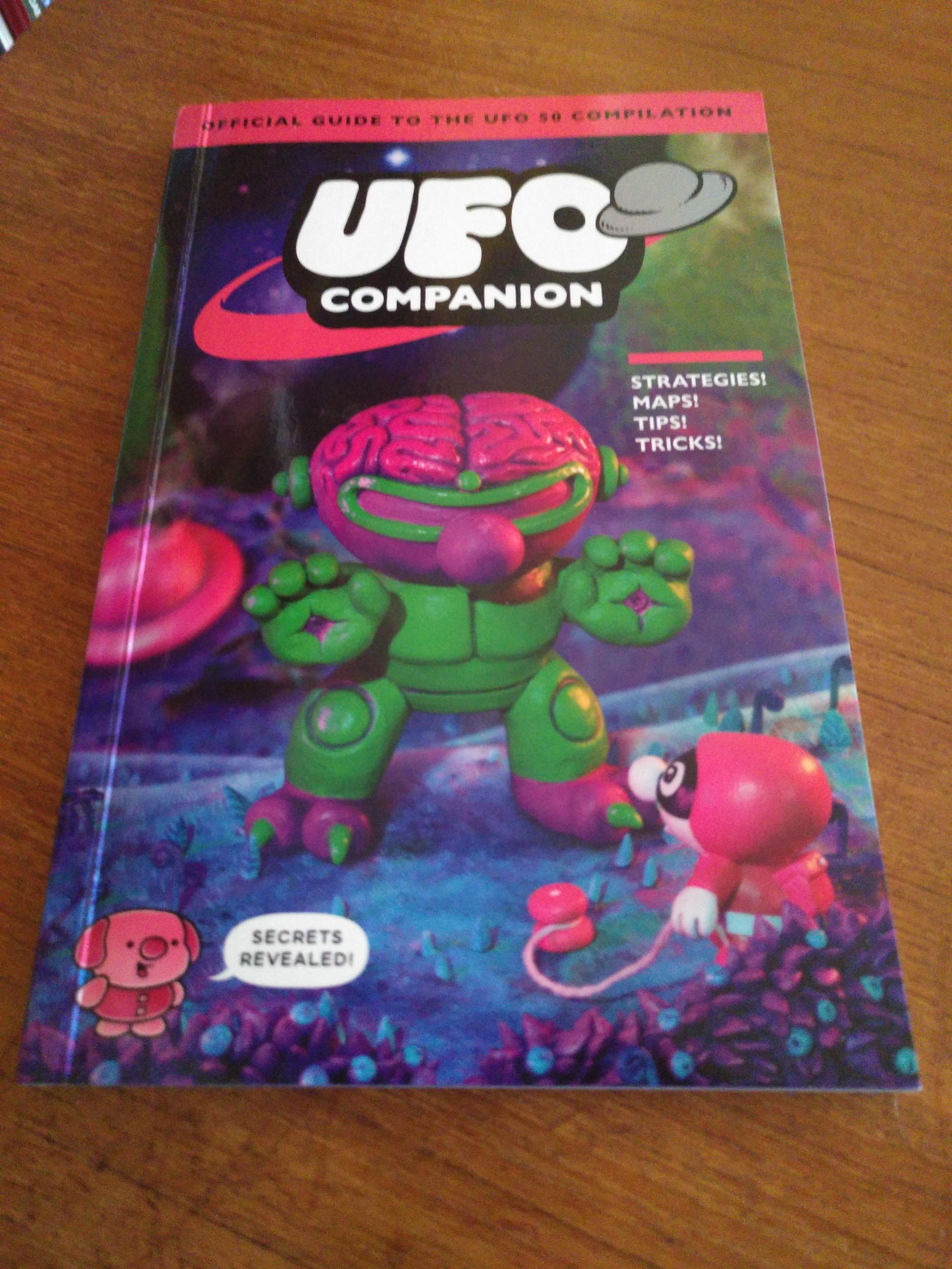 Photo de la cover du livre UFO Companion, un petit livre avec un artwork 3D présentant des mascottes.